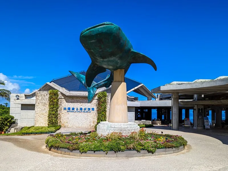 沖縄美ら海水族館の入口、ジンベイザメ像の前で家族が記念撮影