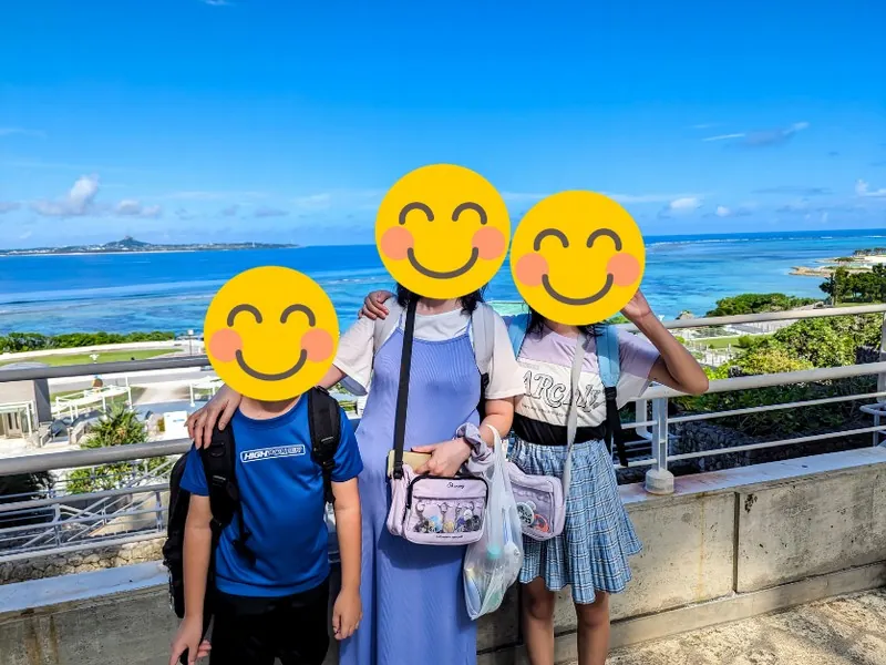 沖縄美ら海水族館外の海を背景に、家族で記念撮影