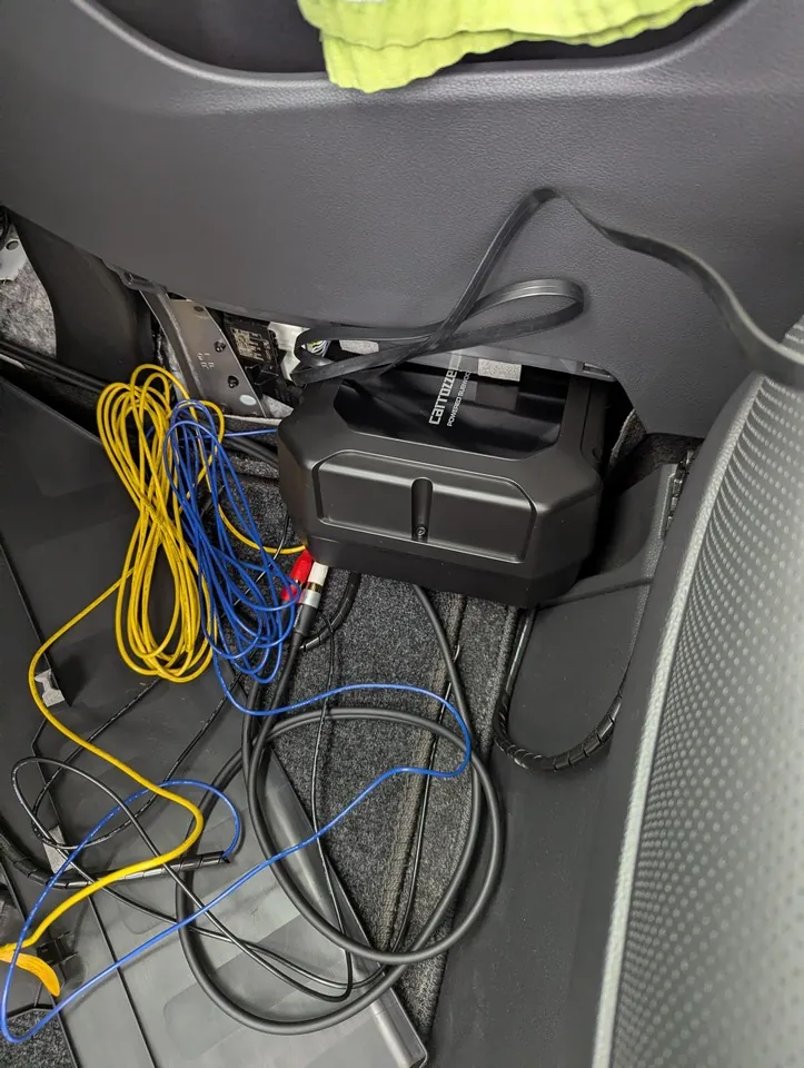 40系アルファードのセンターコンソール下にサブウーファーTS-WX400DAを設置しようとしている様子。サブウーファーが車内スペースに入る途中で、周囲の配線と内装パネルが一部取り外されている