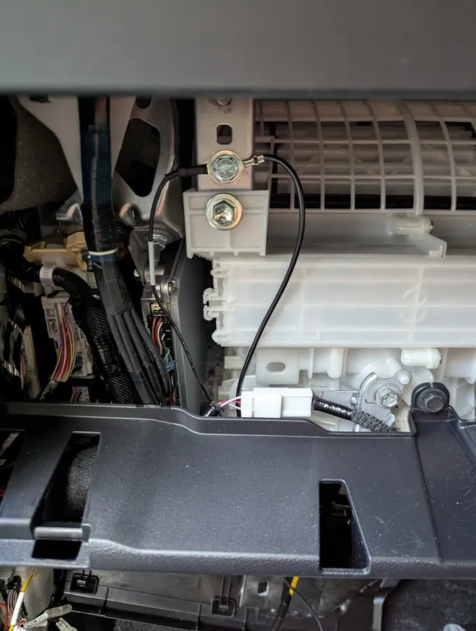 40系アルファードのグローブボックス奥にあるアースポイント。車体剛性部（リーンホースメント）のボルトにリング端子を共締めした様子。