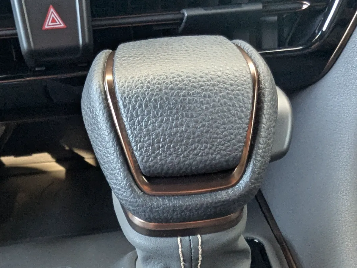 40系アルファード ガソリンZ純正のウレタンシフトノブの接写画像。表面の強いシボ感と、加飾パネルのダークガンメタ色が確認できる写真。